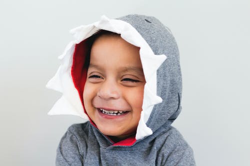 男孩微笑着穿着灰色和白色的连帽的上衣 · 免费素材图片