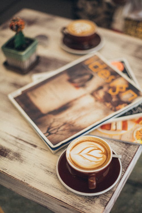 两个拿铁咖啡和棕色托盘上的杂志 · 免费素材图片