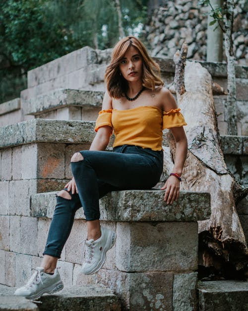 女人坐在树干旁边的混凝土椅子上 · 免费素材图片