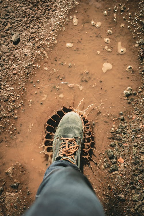 穿灰色鞋子站在棕色的土壤上的男人 · 免费素材图片