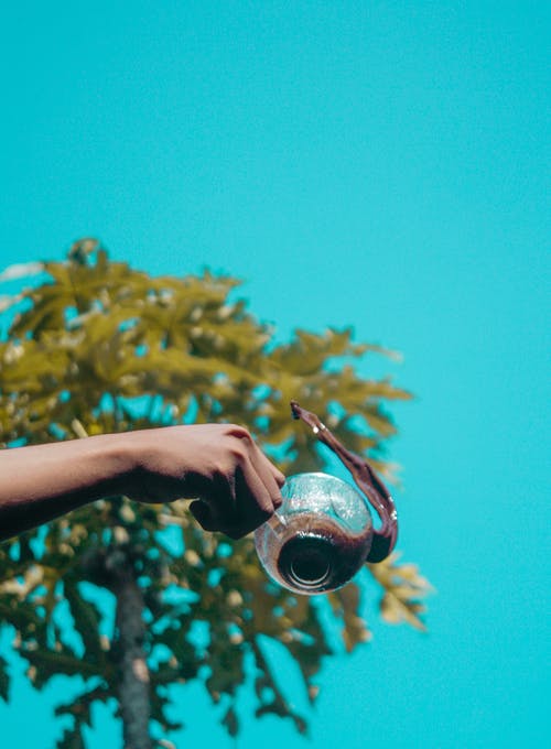 持有透明玻璃杯的人 · 免费素材图片