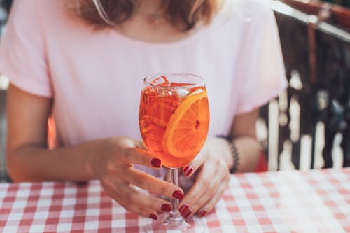 透明长柄酒杯与橙色液体的选择性聚焦摄影 · 免费素材图片
