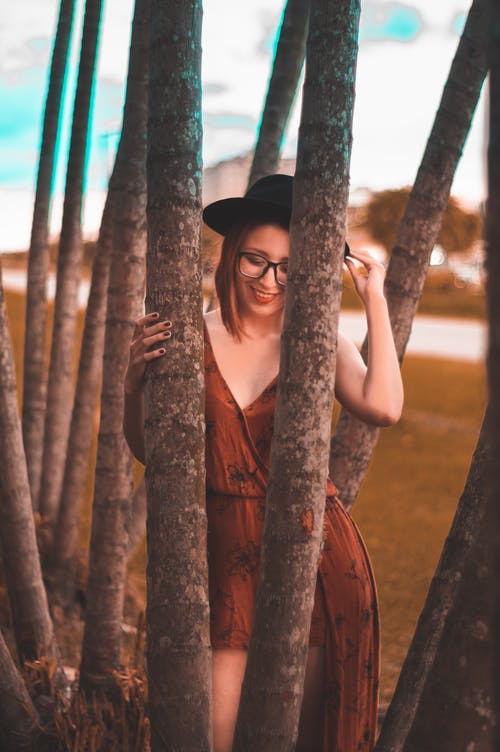 女人穿着棕色的衣服，拿着一棵树 · 免费素材图片