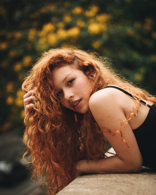 按住她的头发靠在墙上的女人 · 免费素材图片