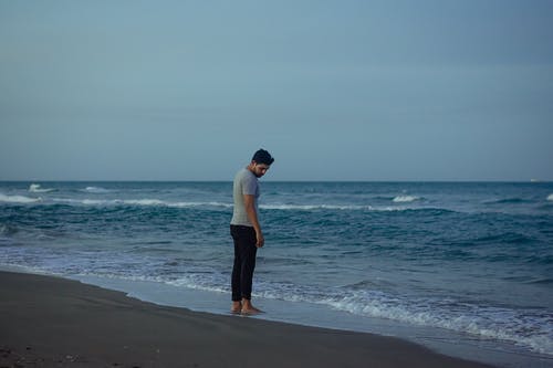 男人穿着灰色衬衫站在岸上 · 免费素材图片