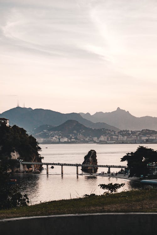 在白色的天空下水体附近的雾山 · 免费素材图片