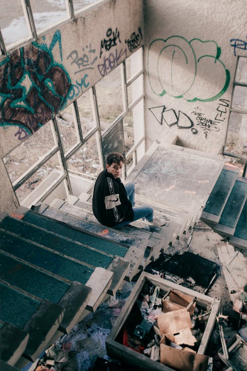 坐在混凝土楼梯上的男人的高角度摄影 · 免费素材图片