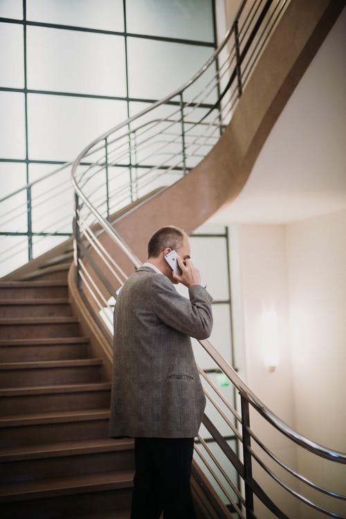 站在楼梯上听智能手机的人 · 免费素材图片