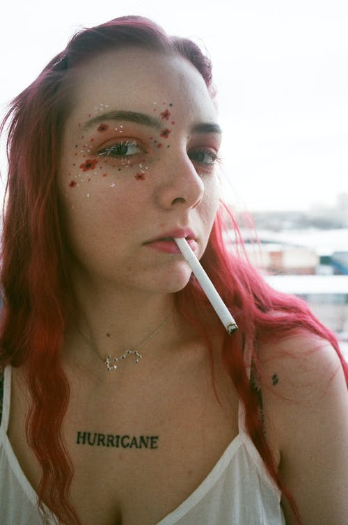 女人的肖像照片与闪闪发光的o她的右眼和香烟在她的嘴摆姿势 · 免费素材图片