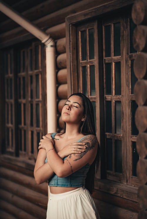 倚在棕色木墙上的女人 · 免费素材图片