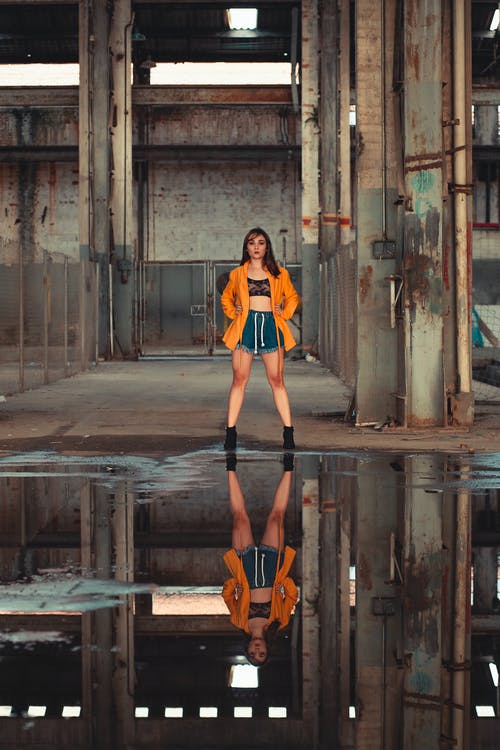 站在水坑前的橙色西装外套的女人 · 免费素材图片