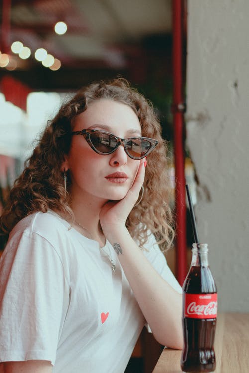 白顶可口可乐瓶附近的女人 · 免费素材图片