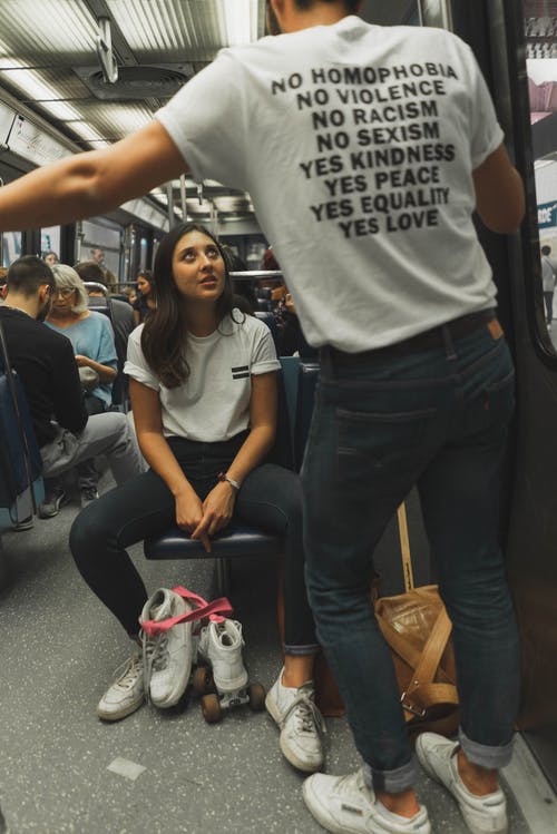 女人穿着白色圆领衬衫和黑色的牛仔裤，坐在火车座位上 · 免费素材图片