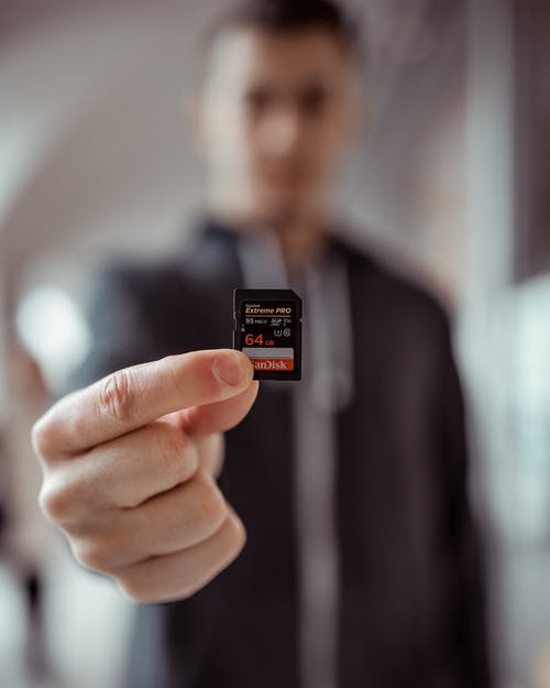 持有sandisk 64 Gb Micro Sd适配器的人 · 免费素材图片