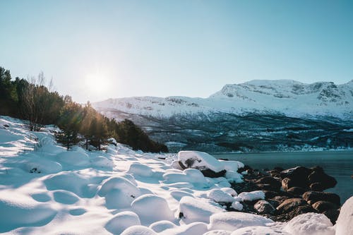 小山附近的海岸上的积雪的岩石 · 免费素材图片