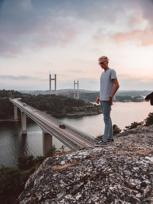 男子站在山俯瞰桥顶 · 免费素材图片