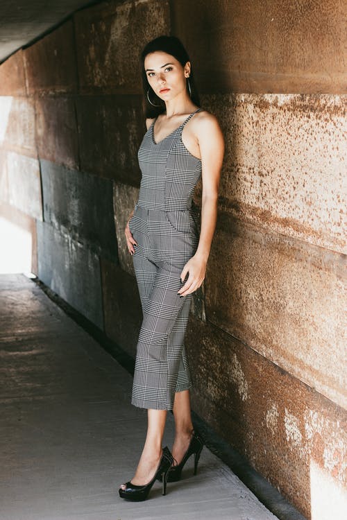 穿灰色无袖连衣裙站在棕色墙附近的女人 · 免费素材图片