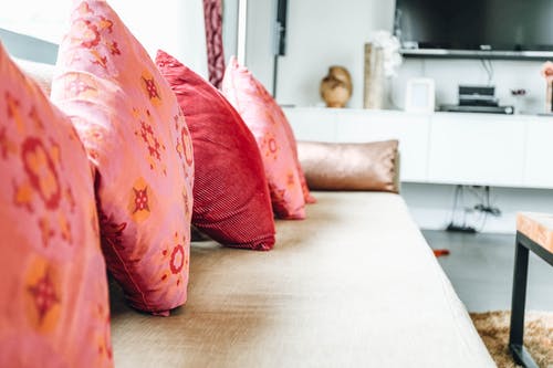 堆在沙发上的四个粉红色扔枕头 · 免费素材图片