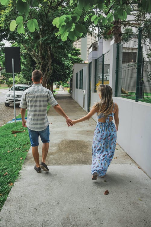 夫妇在人行道上行走时手牵着手的背影照片 · 免费素材图片