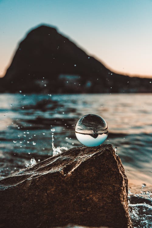 玻璃球在水体附近的浅焦点照片 · 免费素材图片