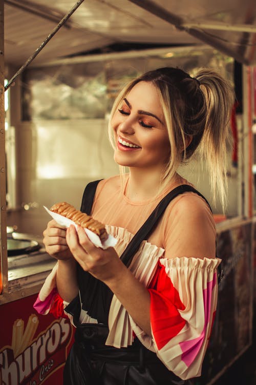 微笑的女人用两只手拿着蛋糕 · 免费素材图片