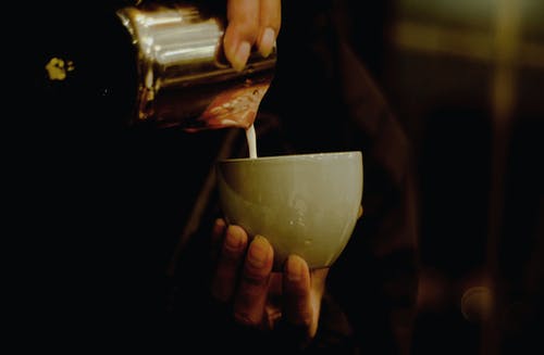 人在陶瓷杯里倒液体 · 免费素材图片