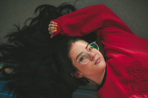 躺在地上的红色圆领运动衫的女人的照片 · 免费素材图片