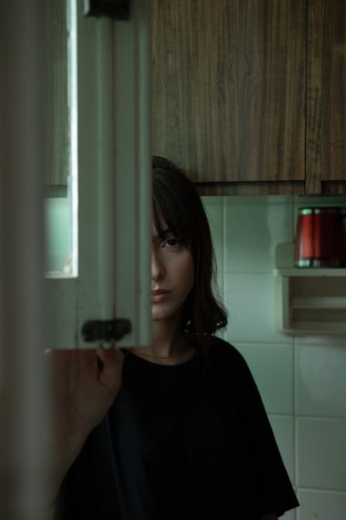 女人站在厨房里穿黑色衬衫的时候站 · 免费素材图片