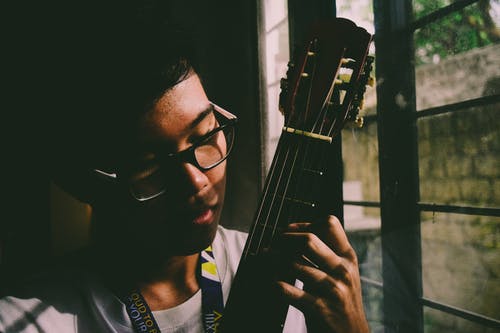 男人在窗户面板附近弹弦乐器 · 免费素材图片