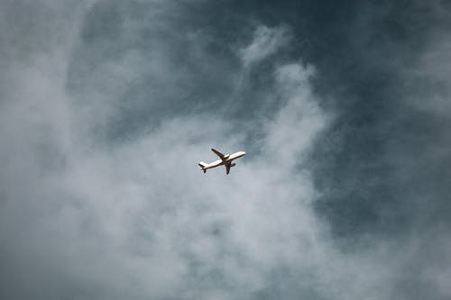 多云的天空下空中的白色飞机 · 免费素材图片