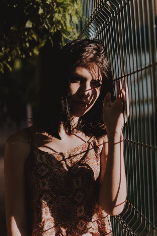 站在黑金属栅栏旁边的女人的照片 · 免费素材图片