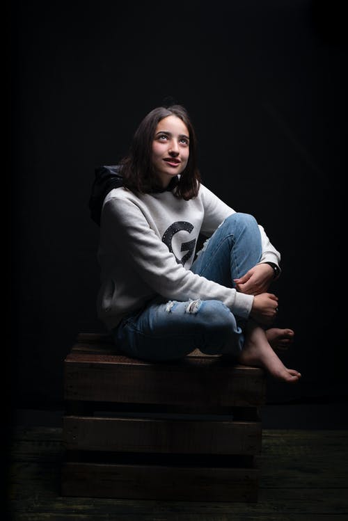 女人坐在棕色木箱上的照片 · 免费素材图片