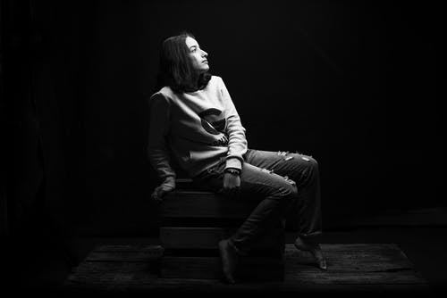 女人坐在木箱上的灰度照片 · 免费素材图片