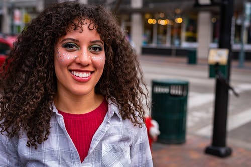 脸上闪闪发光的微笑在街边的女人的肖像照片 · 免费素材图片
