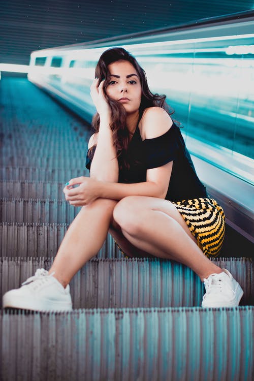 穿黑色上衣，坐在自动扶梯上的女人 · 免费素材图片