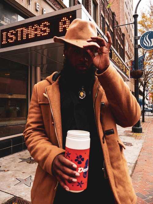 男子手持不倒翁摸他的帽子 · 免费素材图片