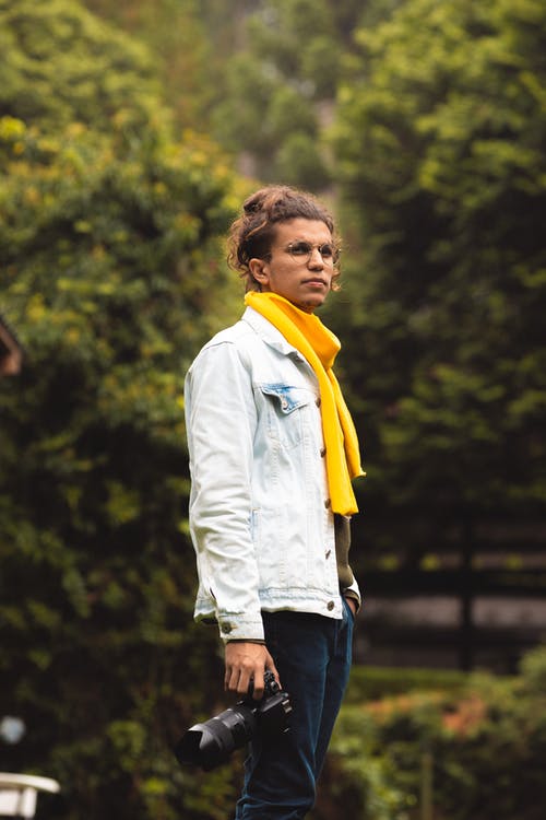 男子手持照相机望着远方的照片 · 免费素材图片