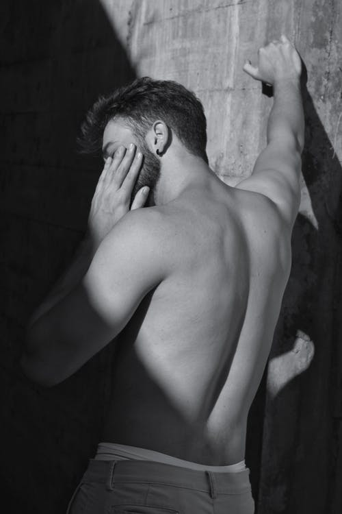 裸照的人，同时触摸他的左脸斜靠在墙上 · 免费素材图片
