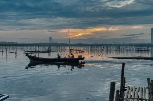 两人骑着小船在灰色的天空下 · 免费素材图片