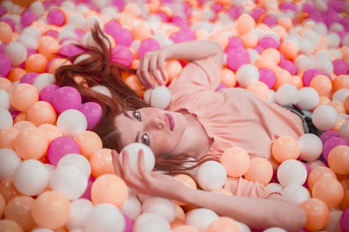 躺在多彩的球池中的女人的照片 · 免费素材图片