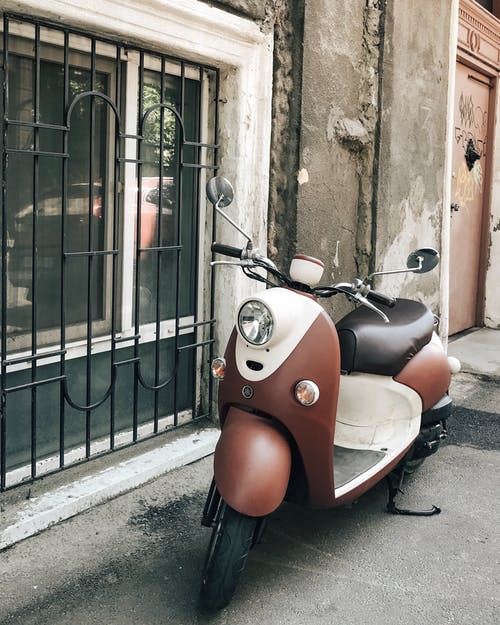 停在窗户附近的棕色和白色摩托车照片 · 免费素材图片