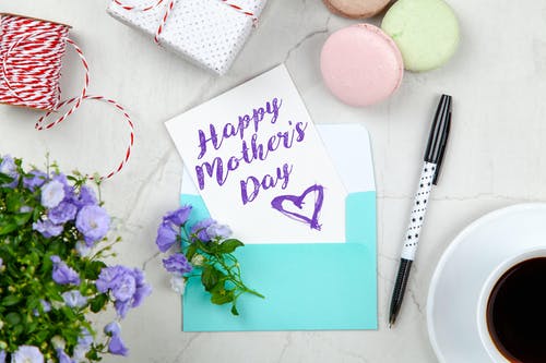 笔，杏仁饼，鲜花和带茶碟的咖啡杯旁的盒子旁边的幸福母亲节贺卡 · 免费素材图片