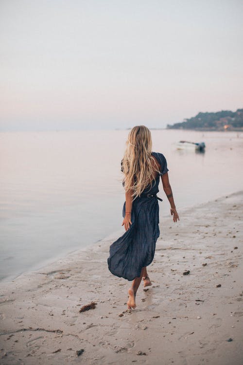 在海边散步的女人的照片 · 免费素材图片