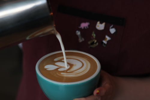 人倒牛奶在咖啡中的特写照片 · 免费素材图片