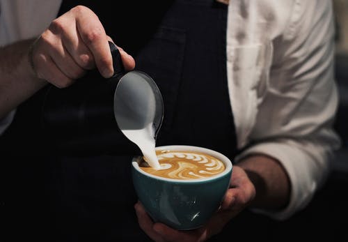 男子倒牛奶在咖啡中的特写照片 · 免费素材图片