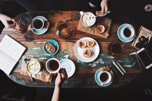 坐在桌子旁边的人与茶杯和盘子 · 免费素材图片