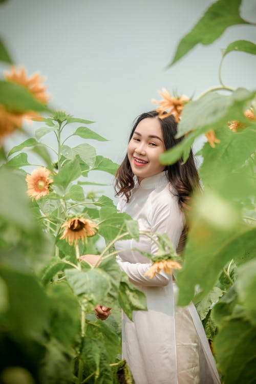 常设女人穿着向日葵包围的白色长袖连衣裙 · 免费素材图片