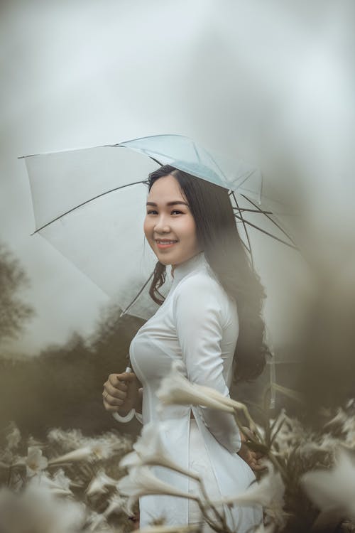 微笑的女士穿着白色的长袖礼服，拿着白色的伞 · 免费素材图片