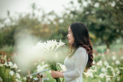 拿着在选择聚焦摄影的白色长袖礼服的妇女白花 · 免费素材图片