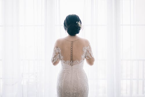 女人穿着白色窗帘附近的白色蕾丝婚纱 · 免费素材图片